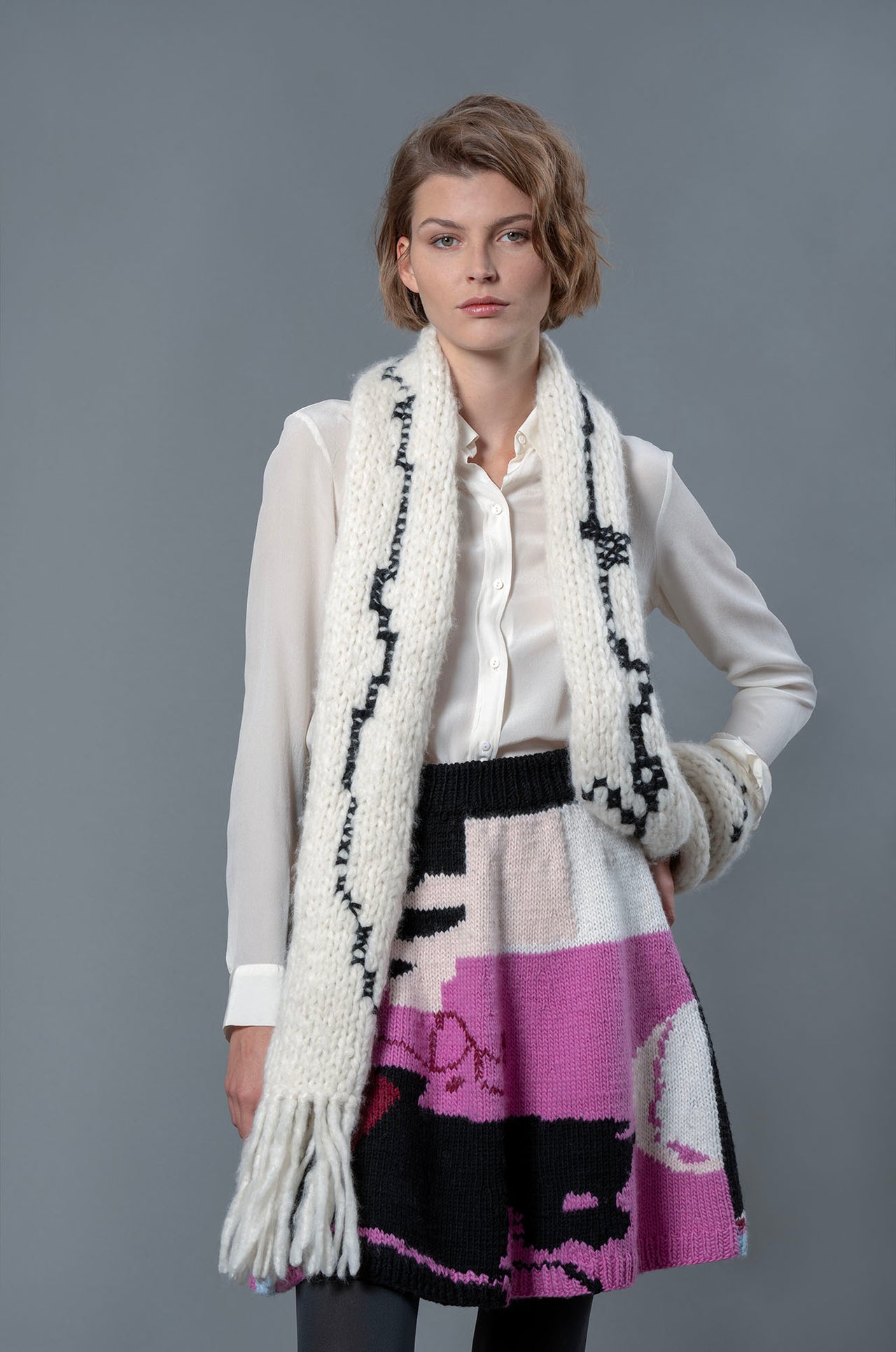 Woman wearing wool skirt and black and white wool scarf. The skirt has abstract colour block patterns in fuchsia, black, white, beige and a touch of burgundy.