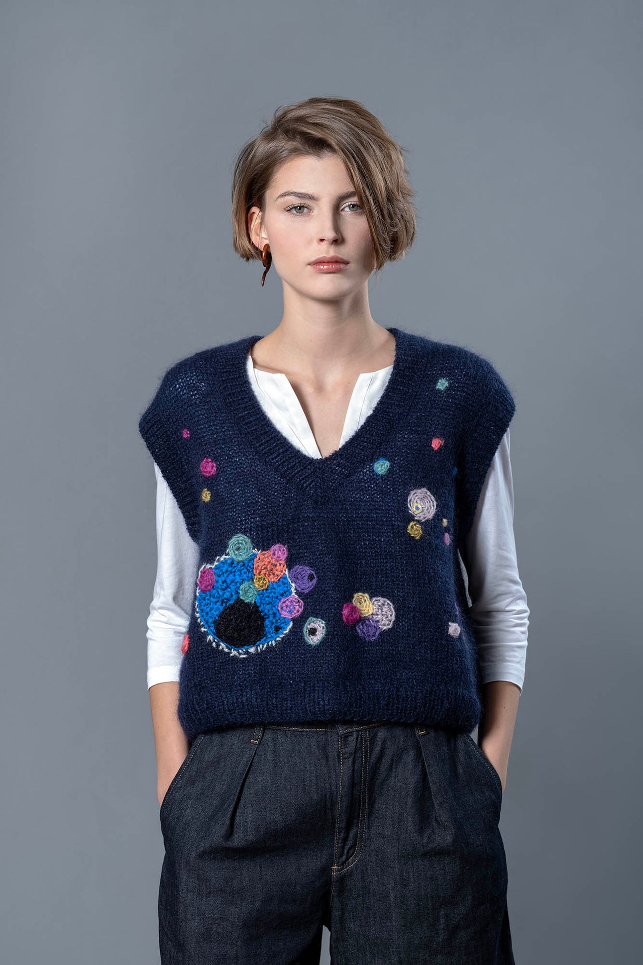Woman wearing mohair navy vest. The vest is adorned with abstract star-like colourful embroideries 