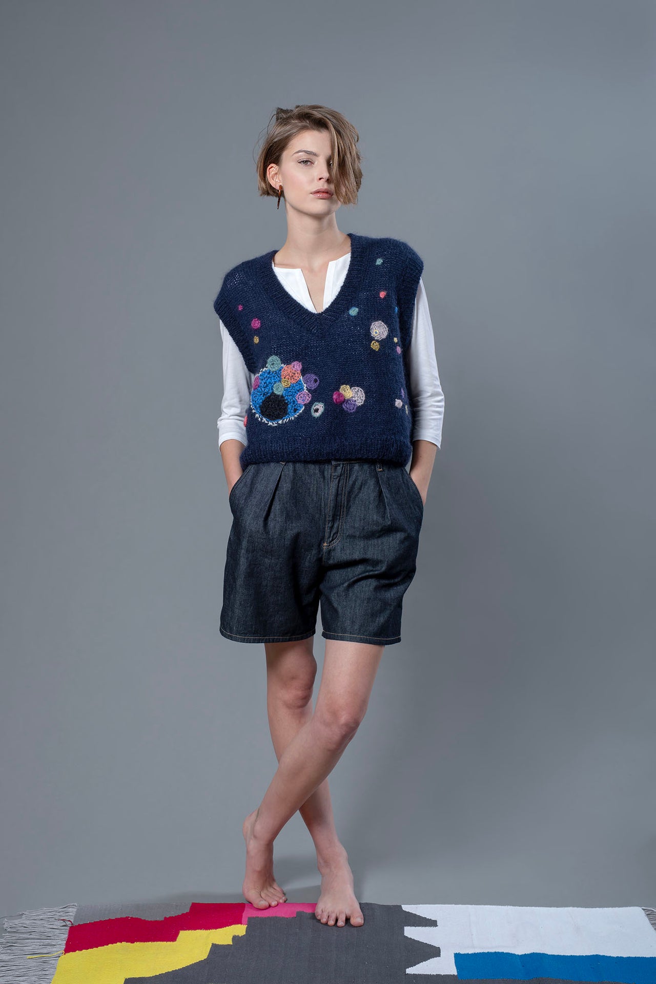 Woman wearing mohair navy vest. The vest is adorned with abstract star-like colourful embroideries 
