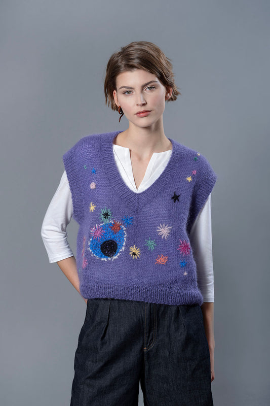 Woman wearing purple mohair vest. The vest is adorned with a multitude of colourful embroideries that resemble flowers.