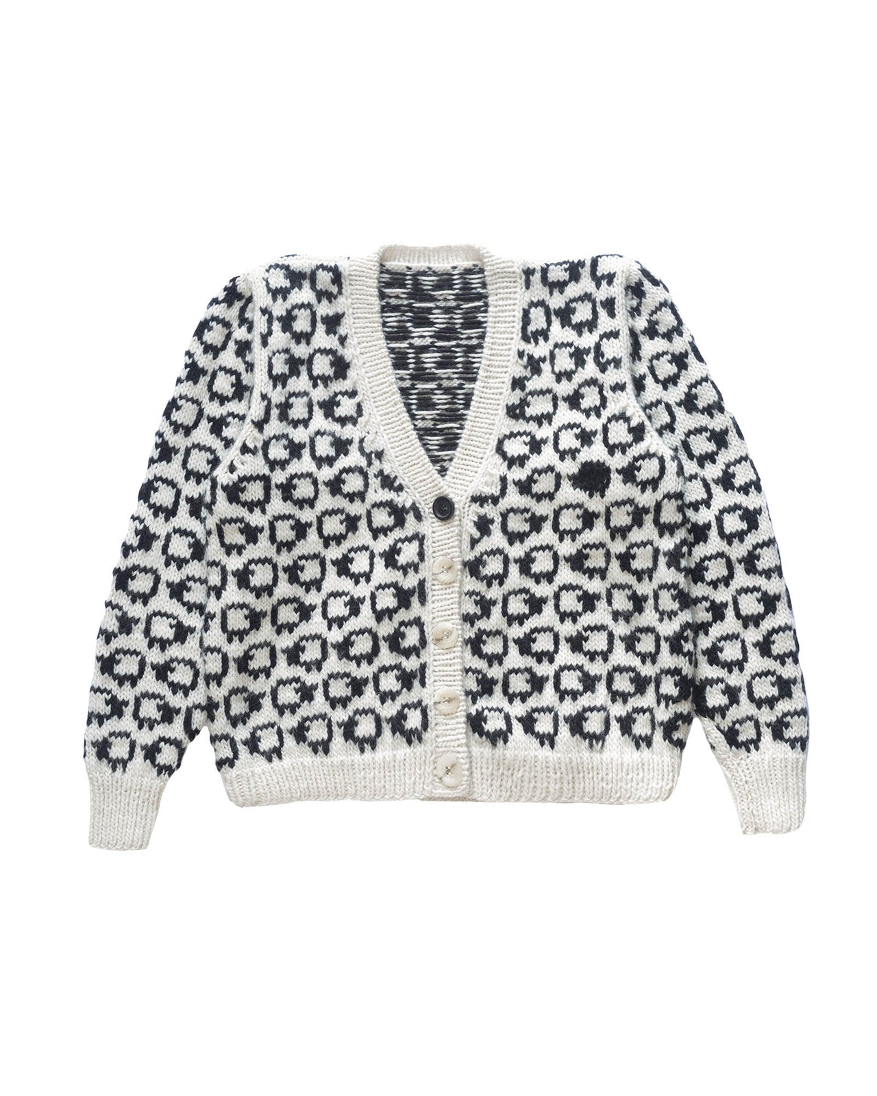Wool cardigan laid flat on white background. The cardigan has a herd of white sheep all over with a single black sheep on the left side.  