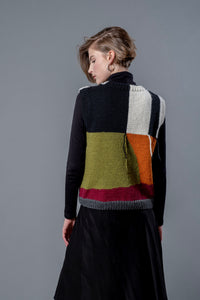 Thumbnail for Women wearing wool vest from behind. Wool vest with green, orange, black, white and red colour block design and hanging threads.