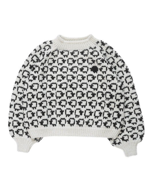 White wool sweater layed flat on white background. On the sweater is a herd of white sheep going left to right all around and a single black sheep on the front. 