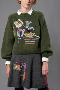 Thumbnail for Woman wearing wool sweater and skirt. A grey skirt with a colourful embroidery on the right leg. 